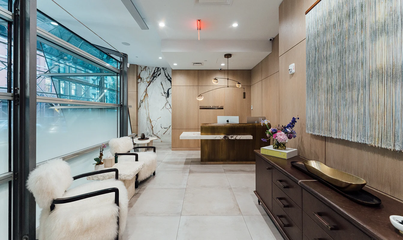 Modern medical office waiting room with white chairs, wood cabinetry, and glass display shelving - in New York , NY