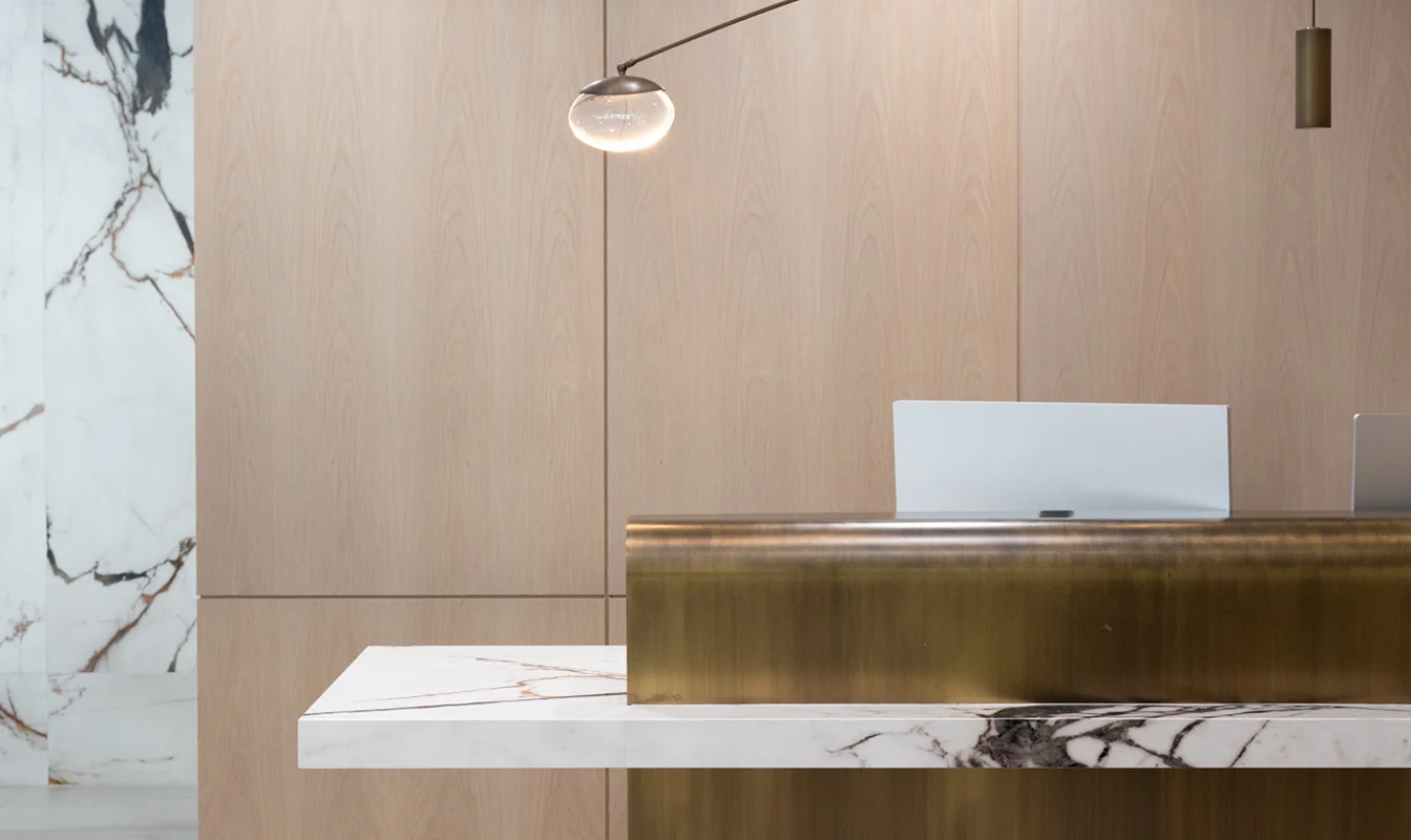Modern minimalist reception desk with brass accent and marble details in neutral-toned lobby interior - in New York , NY