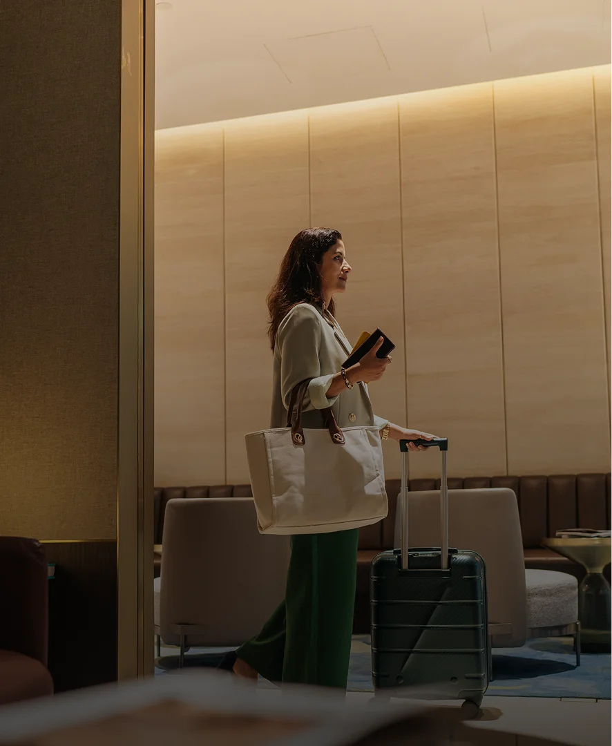 Woman walking with luggage in modern hotel lobby with warm lighting and contemporary interior design - in New York , NY