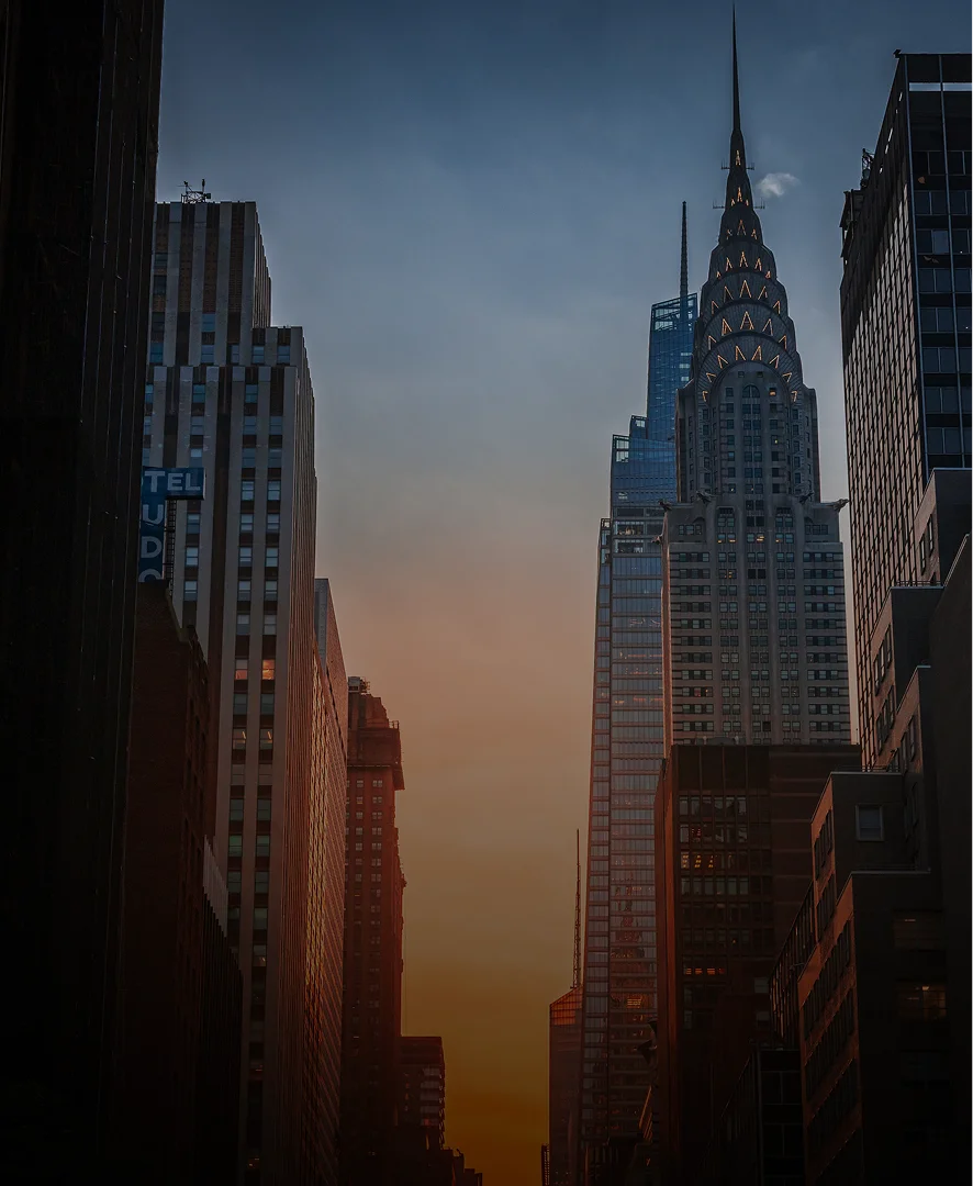 Chrysler Building and Manhattan skyline at sunset with dramatic orange and blue gradient sky