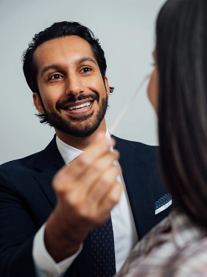 Dr Sameer Halani MD examining patients face while smiling - Botox and wrinkle relaxers in New York , NY