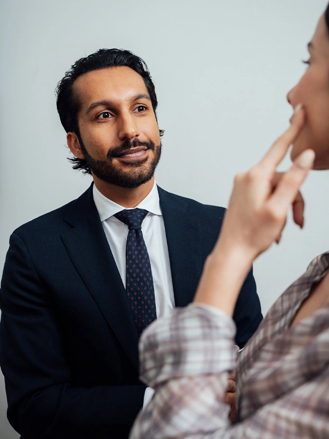 Dr Sameer Halani MD in navy suit listening attentively to colleague during business meeting or consultation - buccal fat removal in New York , NY