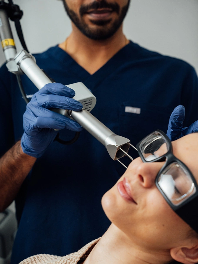 Doctor Sameer Halani performing laser skin treatment on female patient wearing protective eyewear in medical clinic - laser resurfacing in New York , NY