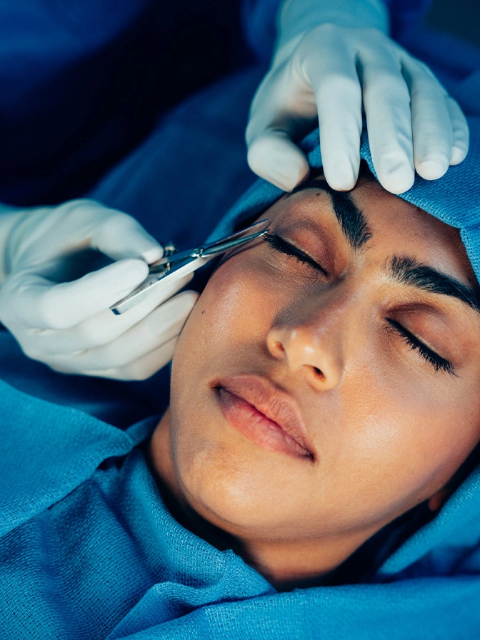 Woman receiving Botox injection treatment in forehead by medical professional wearing blue gloves - temporal browlift in New York , NY